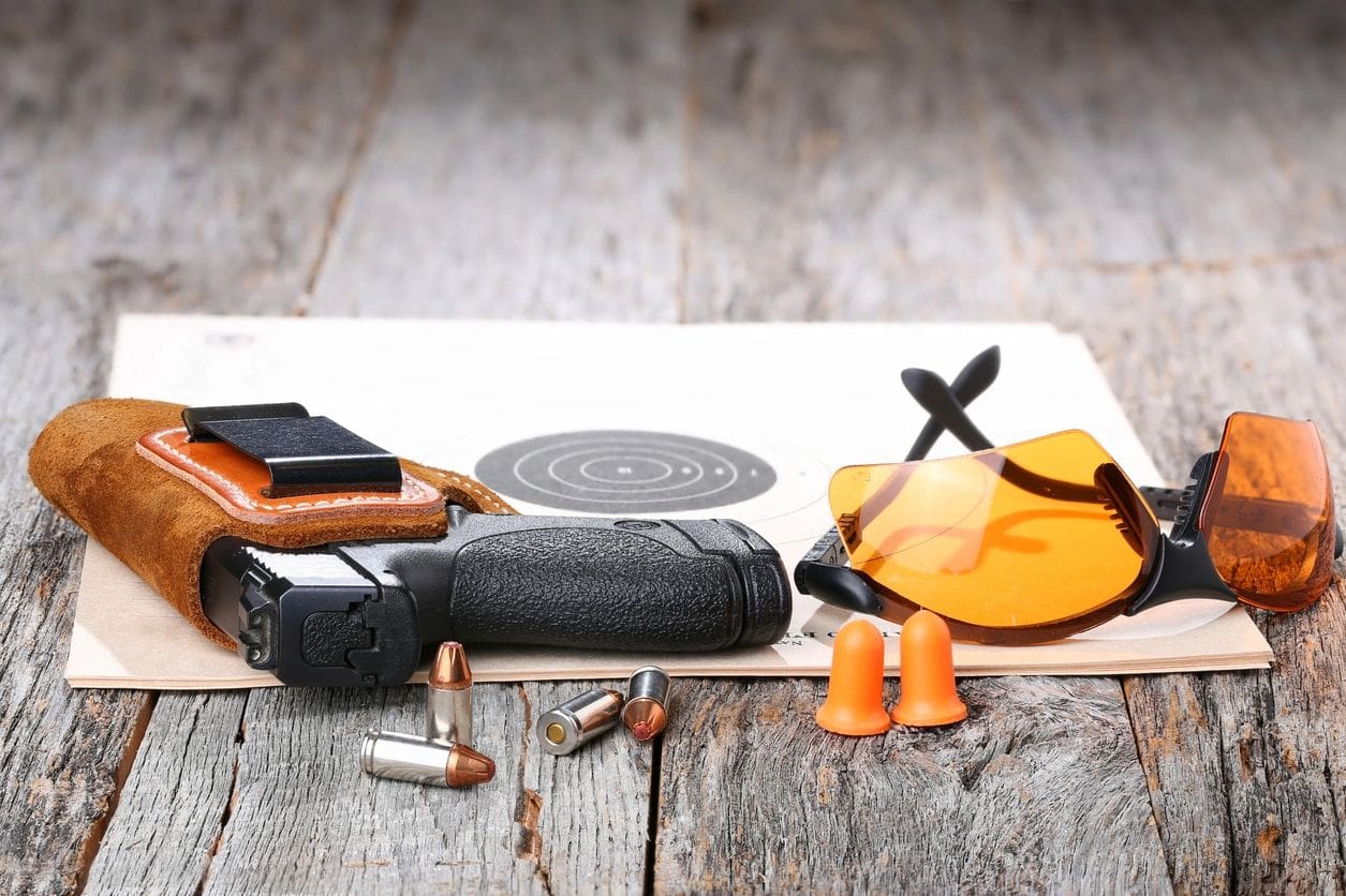 A table with various items on it including a gun, bullet casings and an orange umbrella.