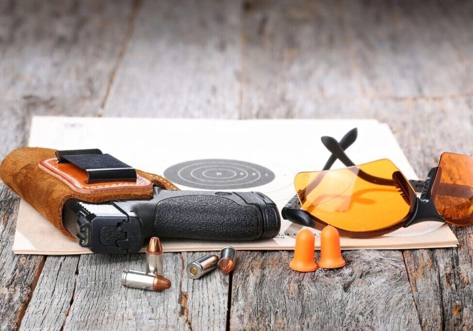 A table with various items on it including a gun, bullet casings and an orange umbrella.